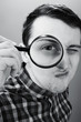 © PumpedVisuals - Young man looking through magnifying glass. Black and white photography.