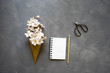 © SianStock - Flowers in ice cream cone with notebook on cement background