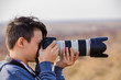 Young male photographer with telephoto in nature