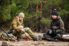 .Two Hunters Are Eating Together In The Forest. Bushcraft, Hunting And People Concept
