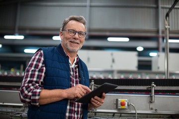 Smiling factory worker using digital tablet in the factory