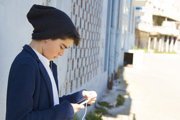 child with a mobile phone in the street about the blue wall