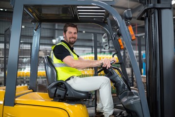 Wall Mural - Portrait of smiling factory worker driving forklift