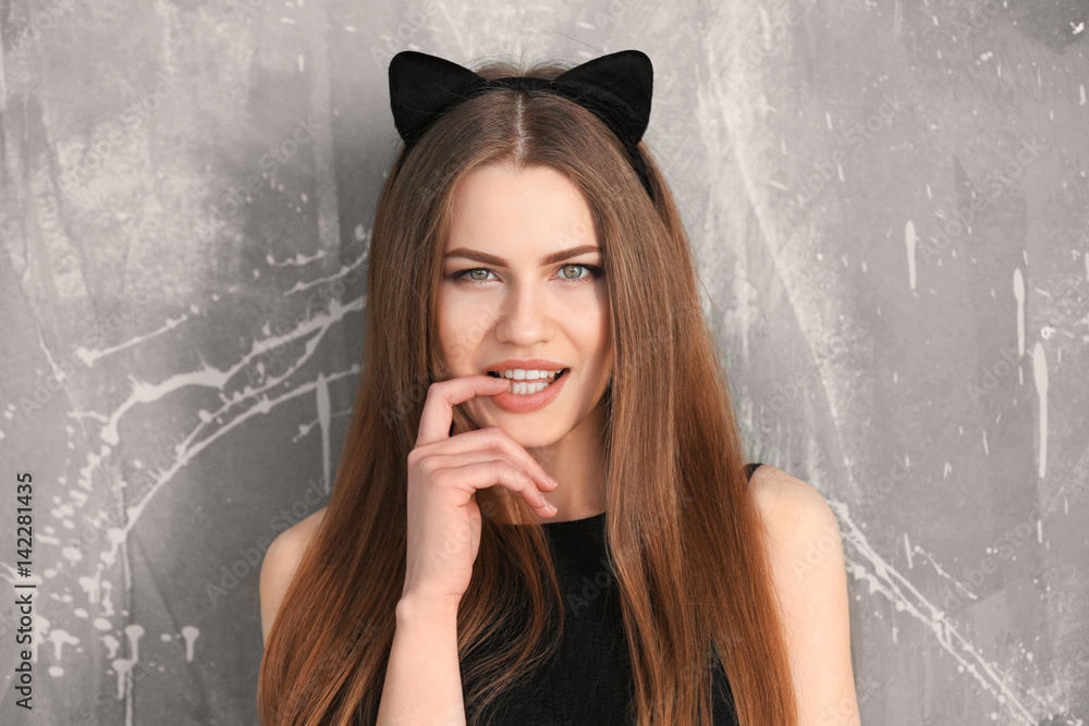 Beautiful young woman with cat ears on grunge background