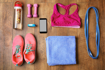 Canvas Print - Fitness tracker and sports clothes and dumbbells on wooden floor, top view