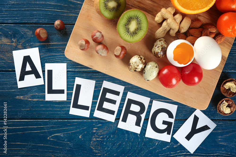 Word ALLERGY and food on wooden background