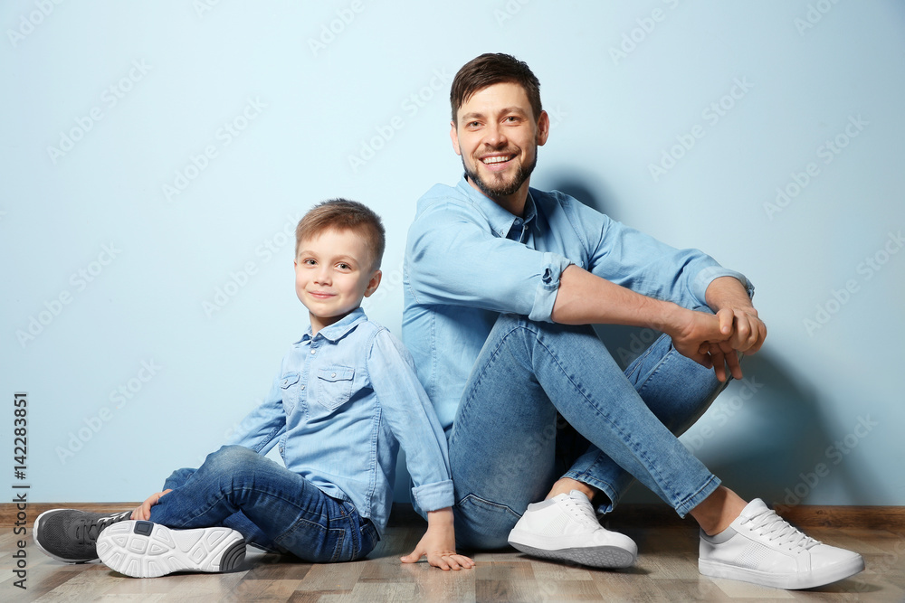 Father and his son sitting on floor near color wall