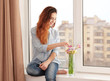 © Africa Studio - Beautiful young woman with bouquet of flowers sitting on window sill at home