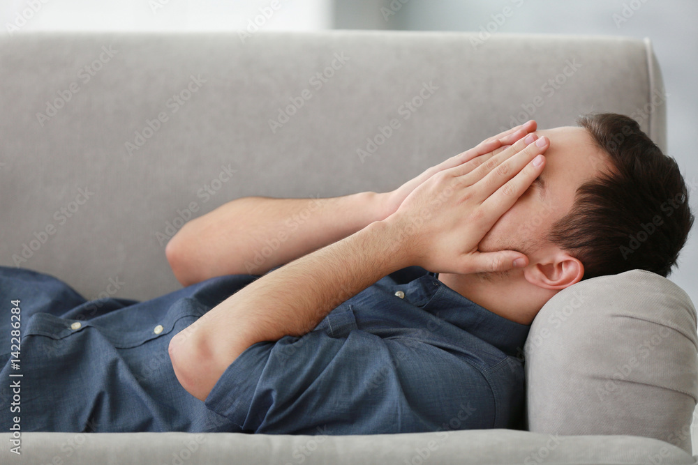 Handsome depressed man on couch at home