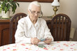 Staruszka liczy pieniądze siedząc przy stole. Emerytura. Stara kobieta liczy pieniądze.