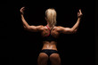 © satyrenko - Beautiful athletic woman in sporty cloths is posing, holding hands up and showing her perfect body, back view isolated on dark background with copyspace