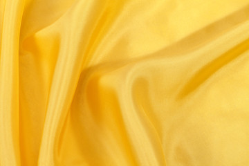 Silk background, texture of yellow shiny fabric