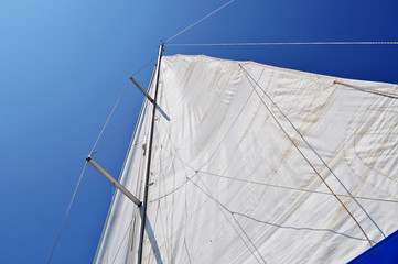  Unfurled mainsail blue sky: Looking up at an unfurled white mainsail with blue sky behind.