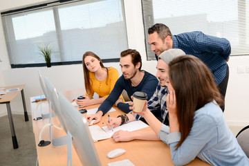 group of five young people student with teacher in computer school classroom learning programming with desktop computer in a row