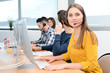 © W PRODUCTION - portrait of beautiful and cheerful young woman telephone operator with headset working on desktop computer in row in customer service call support helpline business center