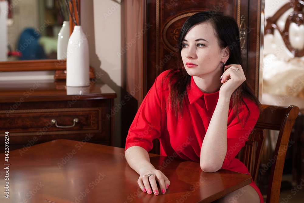 Beautiful girl sitting at a table in a red dress, Stock Photo | Adobe Stock
