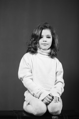 Wall Mural - Little beautiful girl with brown hair in a light sweater. Studio. A princess.