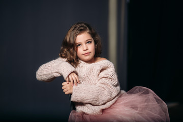 Wall Mural - Little beautiful girl with brown hair in a light sweater. Studio. A princess.