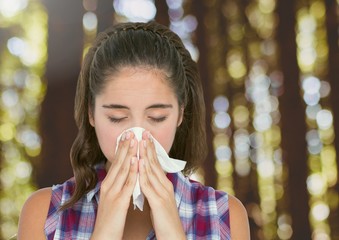 Wall Mural - Young woman with hayfever blowing nose in forest trees