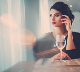 Elegant lady with glass of wine alone in restaurant