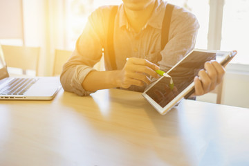 business documents on office table with smart phone and digital tablet and graph financial with social network diagram and man working,while is sitting with laptop computer in co-working cafe.