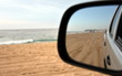 Reflections in a side view mirror of a car driving on the beach. Rear view car mirror. Concept of 4wd off-road driving in the nature.