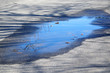 puddle of water on the street reflecting the blue sky