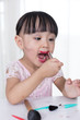 Leinwandbild Motiv Asian Chinese little girl having fun with mess lipstick