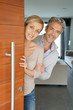 Couple opening house front door to welcome people in