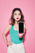 © makistock - Asian girl with professional makeup showing smartphone screen on pink background.