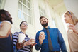 © pressmaster - Waist-up portrait of cheerful young businessman standing outdoors with paper cup of coffee and entertaining colleagues with small talk, low angle view