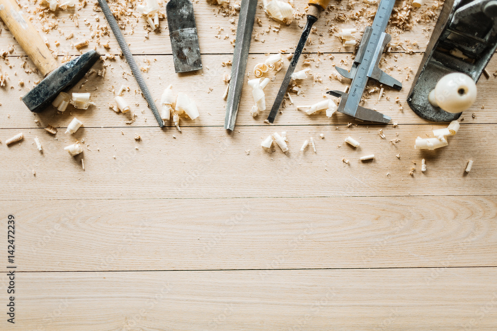 High angle view of shabby woodworking tools lying on wooden table, shavings scattered everywhere - obrazy, fototapety, plakaty 