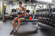 © pressmaster - Portrait of smiling slim woman s listening to music using smartphone while sitting on bench before work out  in gym
