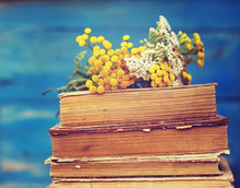 Pile Of Old Books With A Bouquet Of Yellow Flowers Tansy And Yarrow On A Blue Background