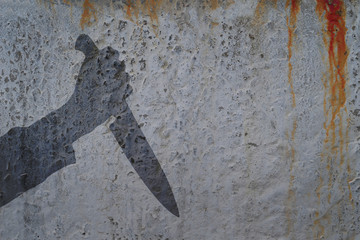 Human hand with killing knife silhouette in shadow on concrete wall and blood background, with space for text or image.