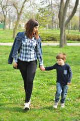 Wall Mural - Happy mom and son play in the park in spring. Mother have quality time with her boy at the park