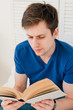 © irina_timokhina - Man reading a book sitting on the bed