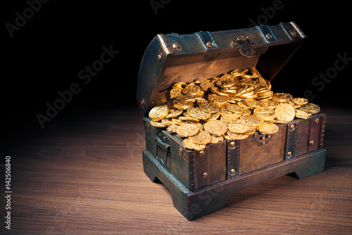 Open treasure chest with gold coins on a dark background