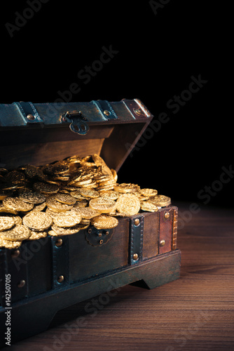 Open treasure chest with gold coins on a dark background