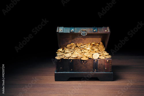 Open treasure chest with gold coins on a dark background