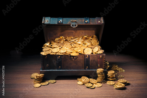 Open treasure chest with gold coins on a dark background