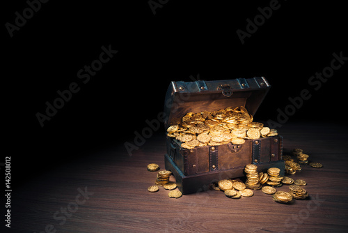 Open treasure chest with gold coins on a dark background