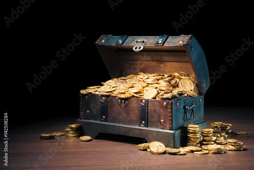 Open treasure chest with gold coins on a dark background