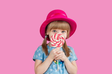 Isolated on bright background, studio. Beautiful little girl with lollipop