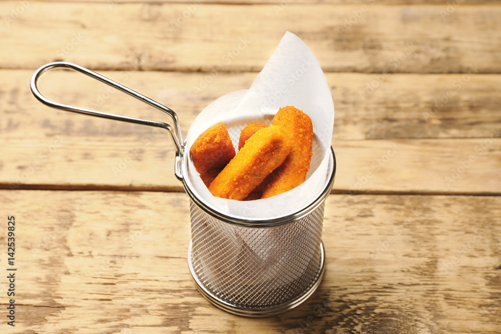 Metal basket with cheese sticks on wooden background