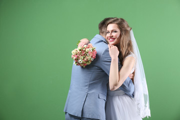 Wall Mural - Happy wedding couple posing on color background