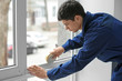 © Africa Studio - Young worker applying rubber strip onto window in office