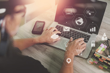 Poster - businessman working with smart phone and laptop computer on wooden desk in modern office with virtual icons interface