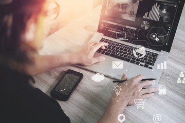 Poster - businessman working with smart phone and laptop computer on wooden desk in modern office with virtual icons interface