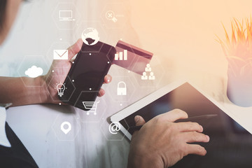 Poster - businessman working with smart phone and digital tablet computer and credit card on wooden desk in modern office with virtual icons interface